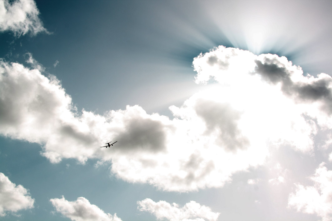 A dynamic photograph of an airplane flying through crepuscular rays